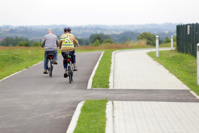 Dw&oacute;ch rowerzyst&oacute;w na drodze rowerowej obok chodnika