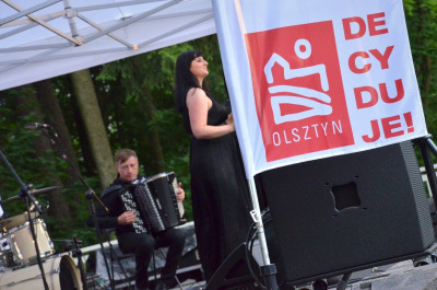 zdjęcie przedstawia akordeonistę, wokalistkę i logo Olsztyńskiego Budżetu Obywatelskiego