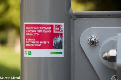 Zdjęcie przedstawia fragment urządzenia siłowni plenerowej z naklejoną wlepką przedstawiającą informację o środkach ionansowych