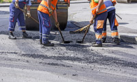 drogowcy naprawiają dziurę w drodze asfaltowej
